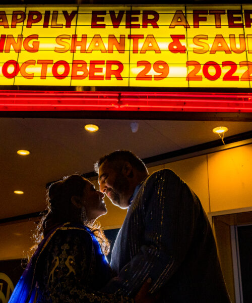 A couple faces each other under a marquee reading "Happily Ever After" with their names and wedding date.