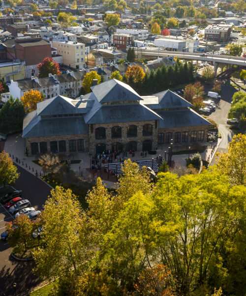 Aerial view of a historic building surrounded by autumn trees and a parking lot in a small town.