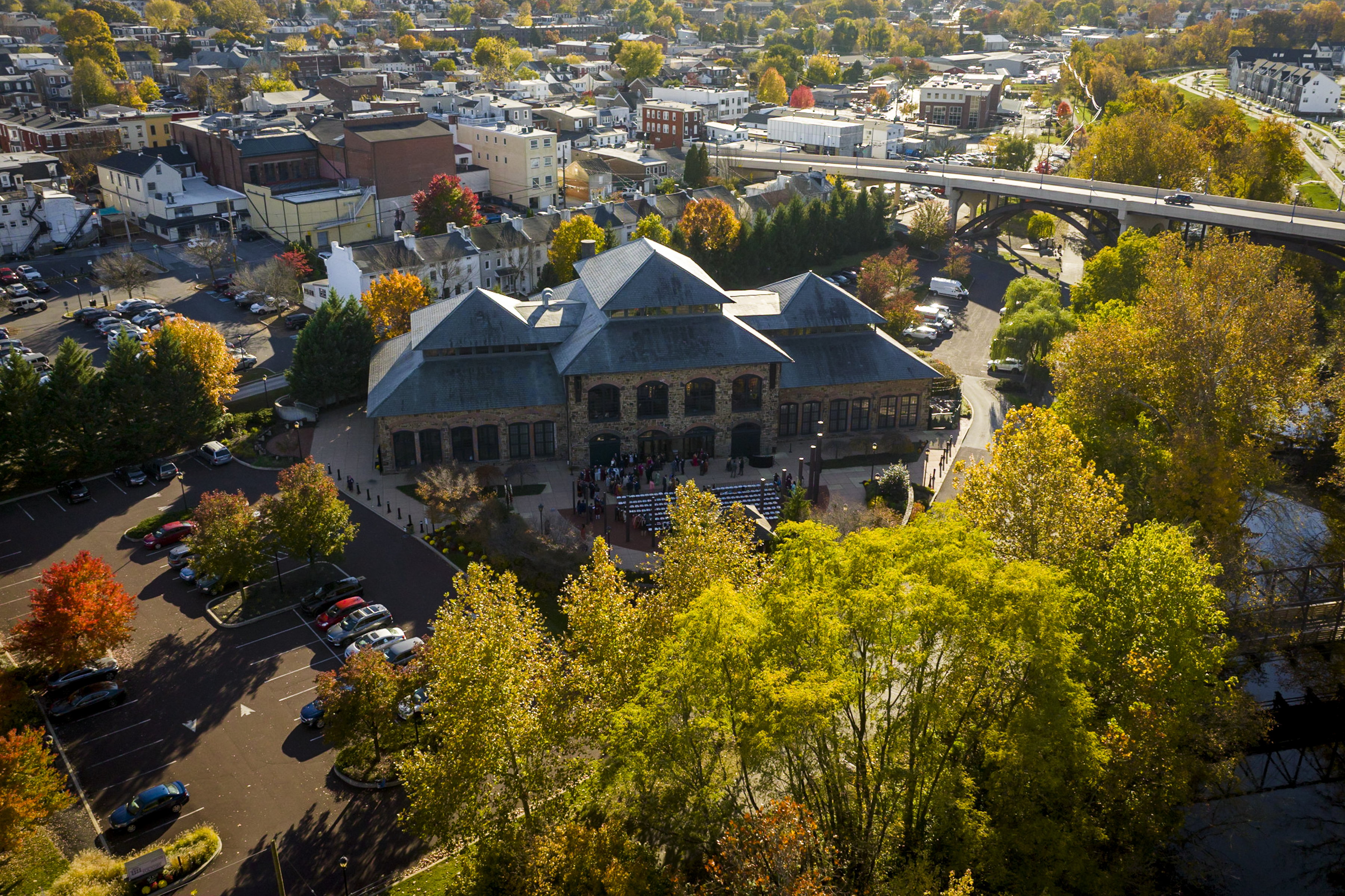 Aerial view of a historic building surrounded by autumn trees and a parking lot in a small town.