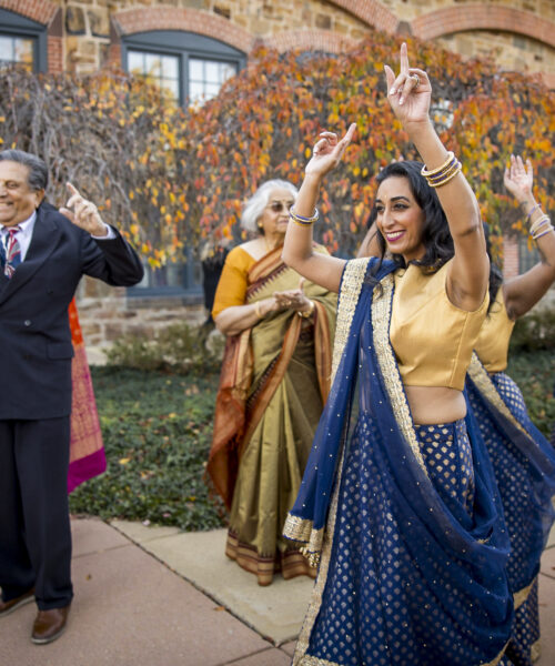 People in colorful traditional Indian attire dance joyfully outdoors during a festive celebration.