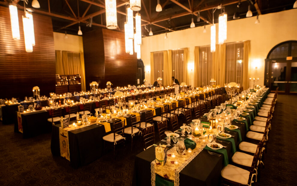 Elegant banquet hall with long tables set for a formal dinner, decorated with candles and soft lighting.