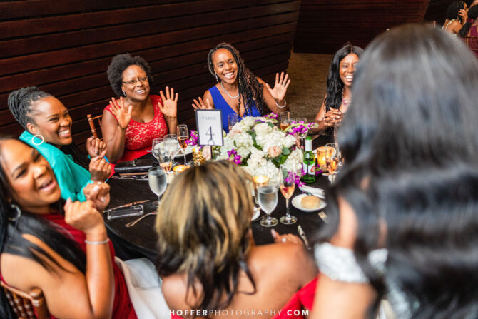 A group of women laughing and smiling around a decorated table at a celebration, table number 4 visible.